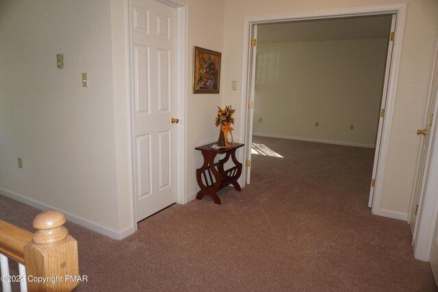 hallway featuring baseboards and carpet