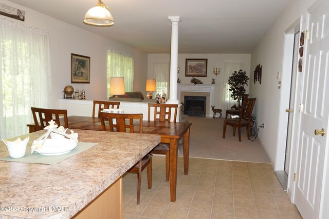 dining space with light tile patterned floors, a fireplace, and ornate columns