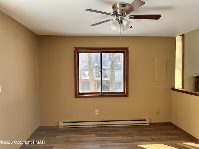 spare room with a baseboard heating unit, wood finished floors, baseboards, and ceiling fan