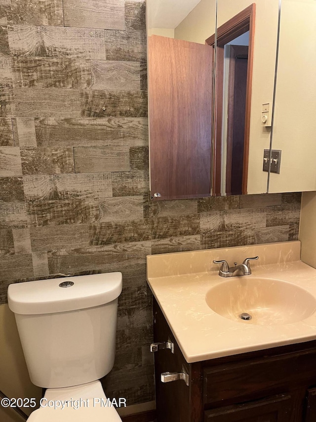 bathroom featuring vanity, tile walls, and toilet