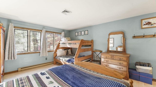 bedroom with baseboard heating, baseboards, visible vents, and wood finished floors