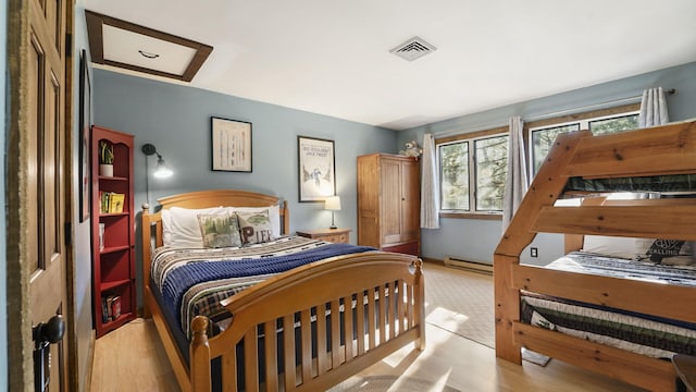 bedroom featuring visible vents, attic access, wood finished floors, and a baseboard radiator