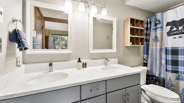 full bathroom featuring double vanity, curtained shower, toilet, and a sink