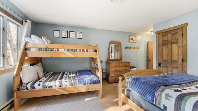 bedroom with a baseboard heating unit and wood finished floors