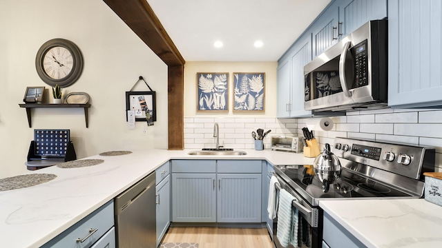 kitchen featuring light stone counters, stainless steel appliances, tasteful backsplash, and a sink