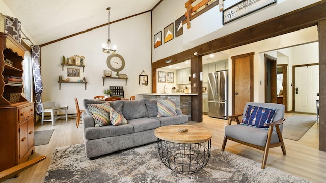 living area with a notable chandelier, light wood-style flooring, high vaulted ceiling, and ornamental molding