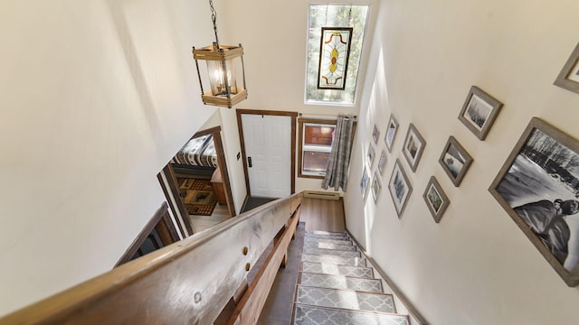 stairs with wood finished floors, a towering ceiling, and a chandelier