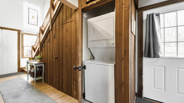 clothes washing area with stacked washer / dryer, light wood-style flooring, and laundry area