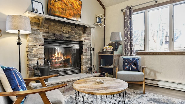 sitting room featuring wood finished floors, baseboard heating, a fireplace, and lofted ceiling