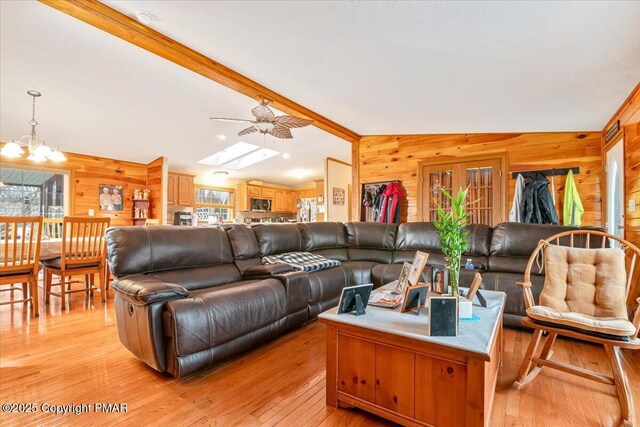 living room featuring lofted ceiling with skylight, plenty of natural light, and wooden walls