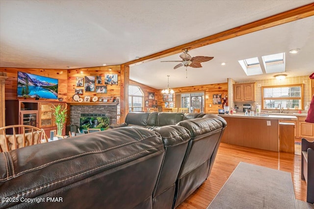 living area featuring wooden walls, plenty of natural light, a fireplace, and light wood-style floors