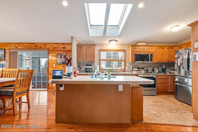 kitchen featuring a skylight, a kitchen island, appliances with stainless steel finishes, and light countertops