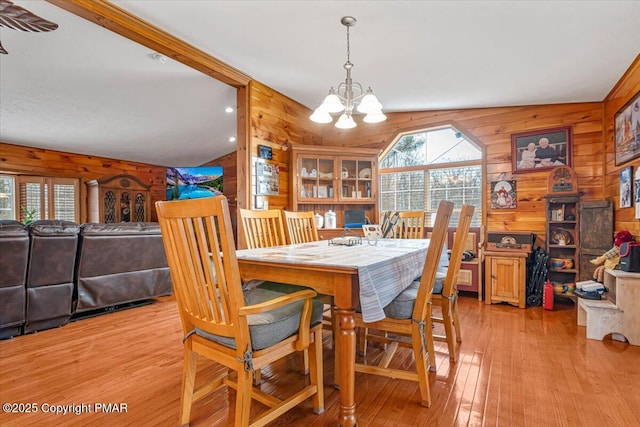 dining area with light wood-style floors, plenty of natural light, and wooden walls