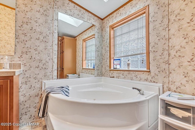 full bath with a skylight, a garden tub, crown molding, vanity, and wallpapered walls