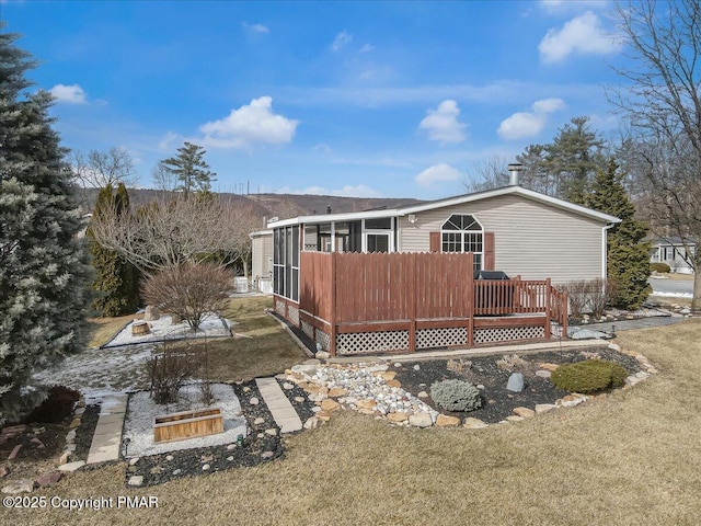 back of property with a sunroom, a lawn, and a wooden deck