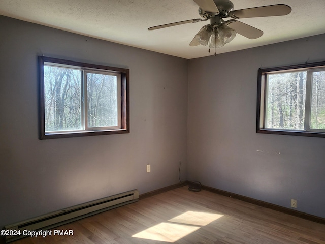 2153 Gravel Rd, Canadensis, PA 18325 - unfurnished room featuring a baseboard heating unit, a textured ceiling, baseboards, and wood finished floors