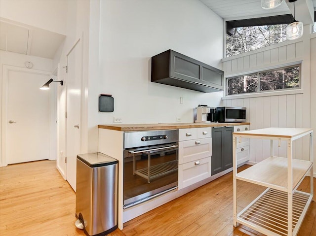 1109 Cedar Knoll Way, Pocono Pines, PA 18350 - kitchen with stainless steel appliances, light wood-style flooring, a high ceiling, and wall chimney range hood