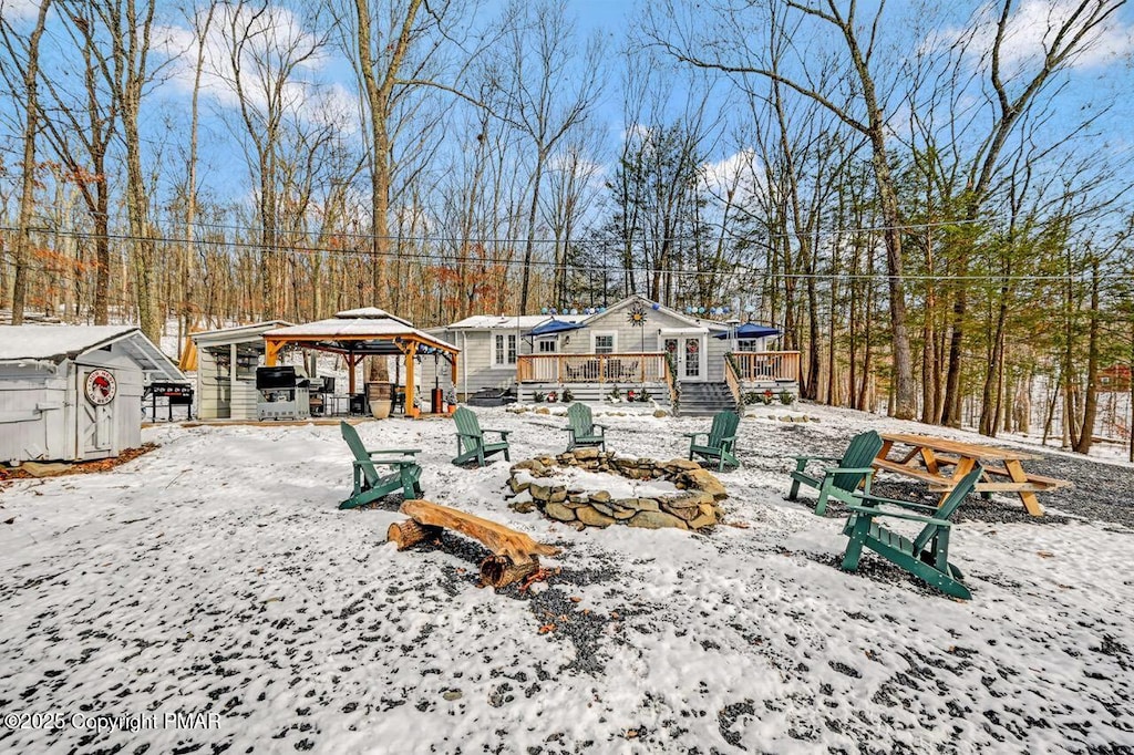 snow covered property with a gazebo, a wooden deck, and an outbuilding