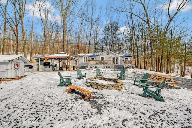 snow covered property with a gazebo, a wooden deck, and an outbuilding