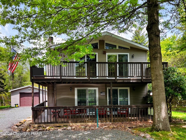 view of front of house with a garage, a wooden deck, and an outdoor structure