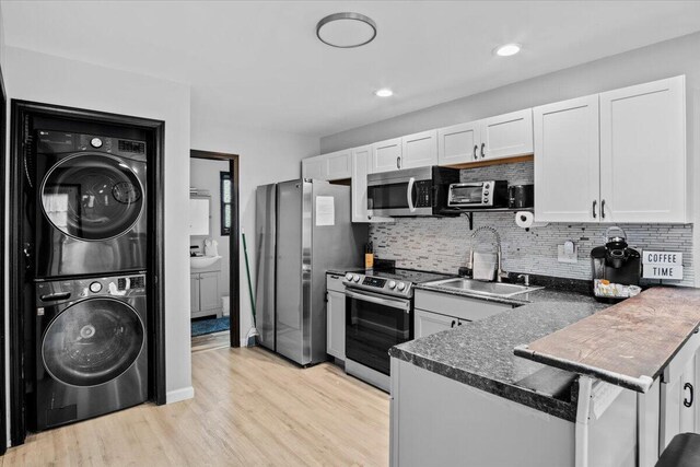 1150 Country Place Dr, Tobyhanna, PA 18466 - kitchen featuring a peninsula, dark countertops, appliances with stainless steel finishes, a sink, and stacked washing maching and dryer