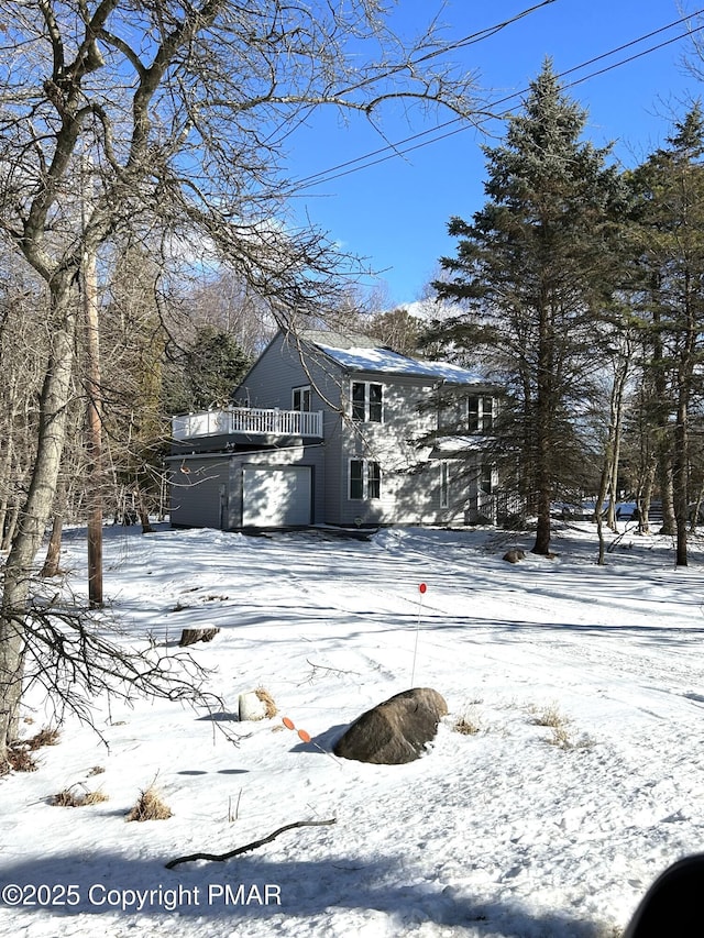 view of snow covered exterior with a garage and a balcony