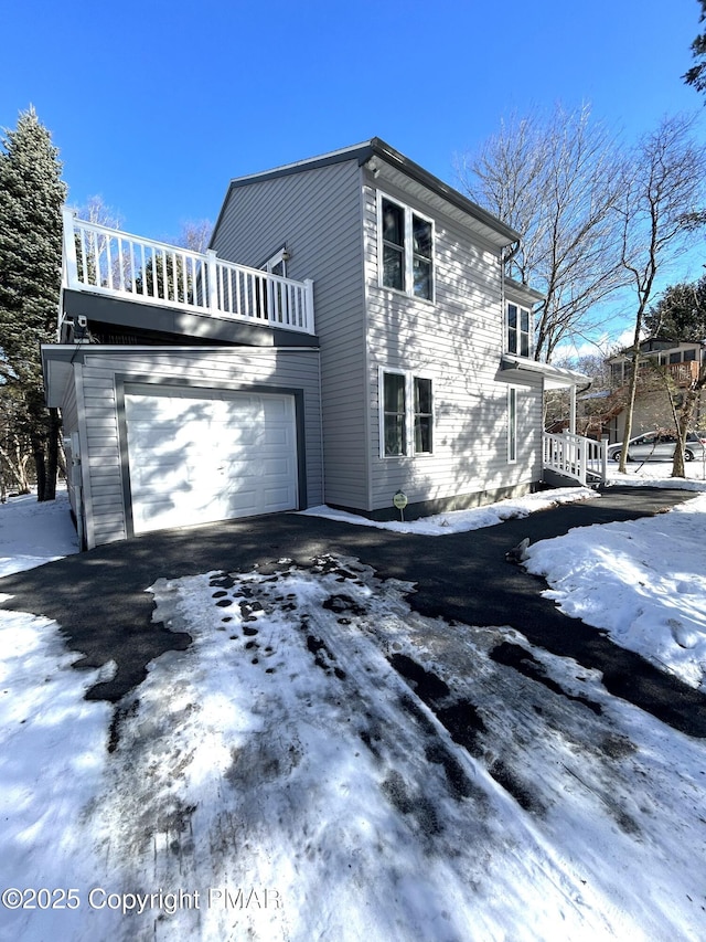 view of snow covered exterior with a balcony and a garage