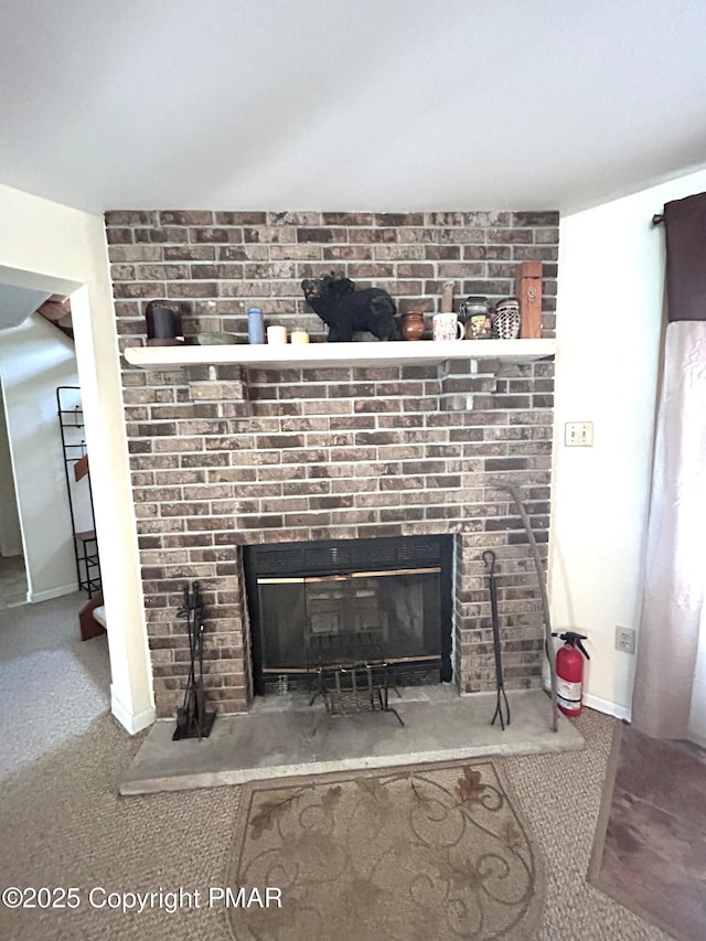 interior details with carpet, a brick fireplace, baseboards, and a fire extinguisher