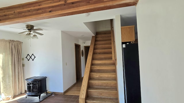 stairs featuring tile patterned floors, a wood stove, baseboards, and ceiling fan