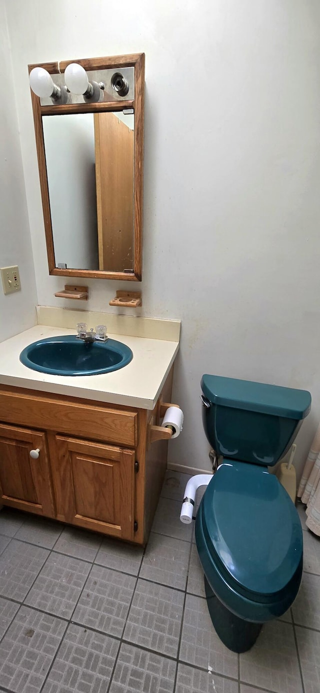 bathroom with toilet, vanity, and tile patterned flooring