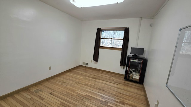 unfurnished room featuring light wood-style flooring, baseboards, and visible vents