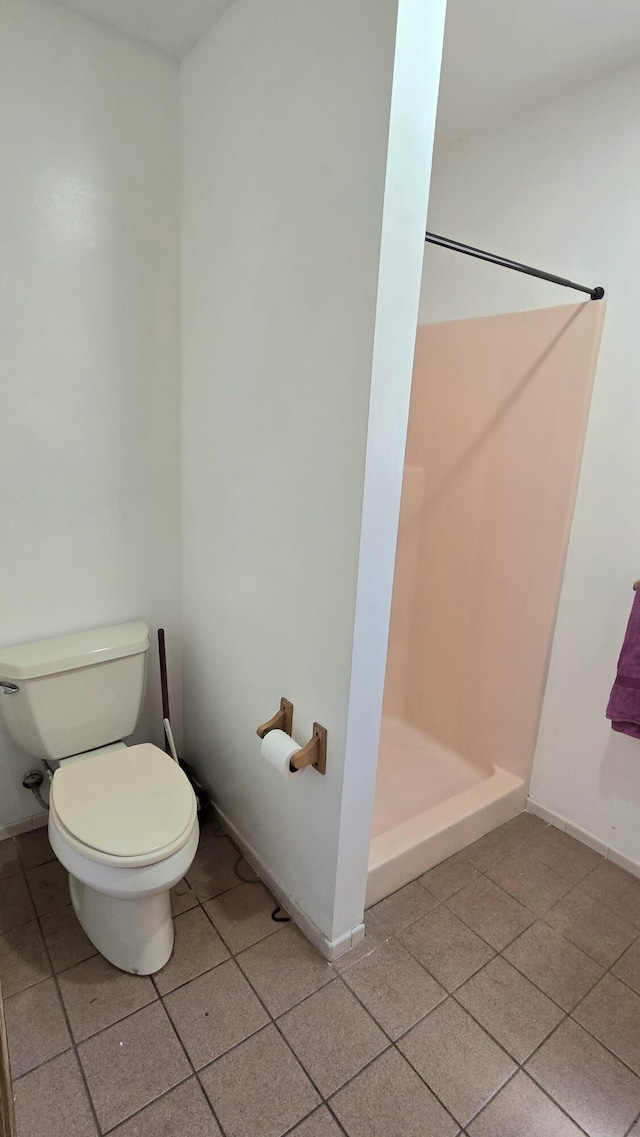 bathroom with tile patterned floors, toilet, baseboards, and a stall shower