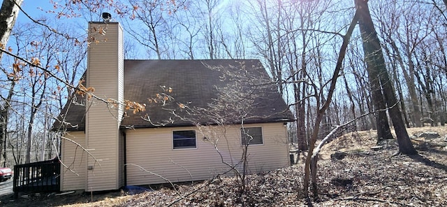 view of side of home featuring roof with shingles and a chimney