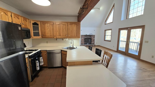 kitchen featuring light countertops, a peninsula, french doors, black appliances, and a sink