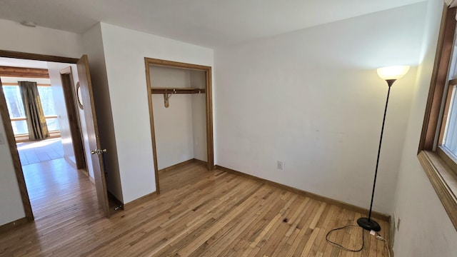 unfurnished bedroom with a closet, light wood-style flooring, and baseboards