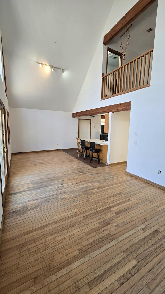 interior space featuring baseboards, high vaulted ceiling, and hardwood / wood-style floors