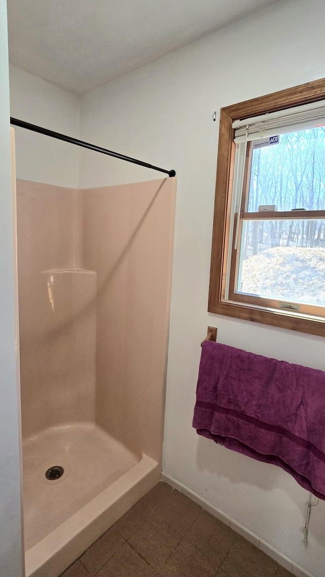 bathroom featuring tile patterned floors, baseboards, and a shower stall