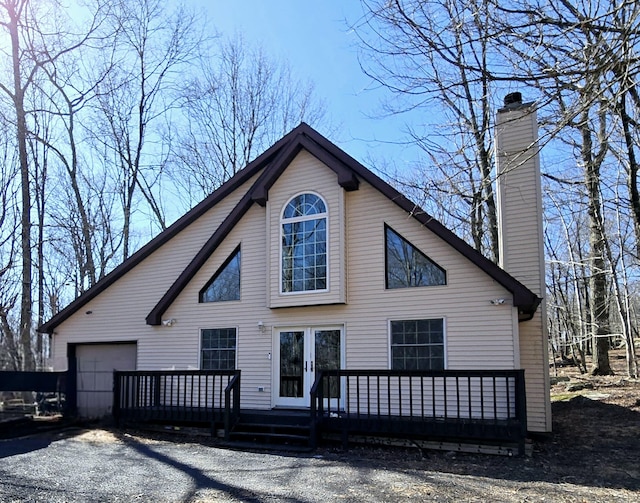 chalet / cabin with a wooden deck, a garage, and a chimney