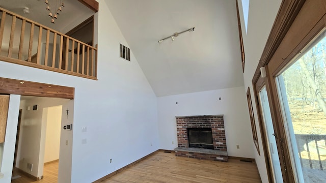 unfurnished living room featuring visible vents, plenty of natural light, high vaulted ceiling, and wood finished floors