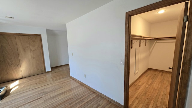 unfurnished bedroom with visible vents, baseboards, a closet, and light wood-type flooring