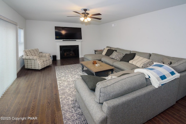 living room featuring a glass covered fireplace, wood finished floors, and a ceiling fan