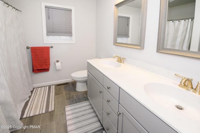 full bath featuring a sink, baseboards, toilet, and double vanity