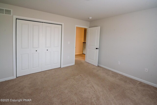 unfurnished bedroom featuring a closet and light carpet