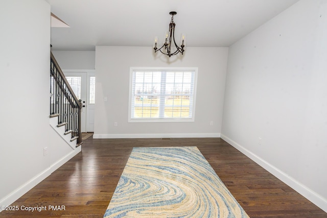 entrance foyer featuring stairway, baseboards, dark wood-type flooring, and an inviting chandelier