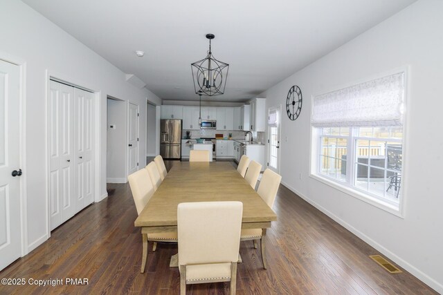 dining area with sink, dark hardwood / wood-style floors, and a chandelier