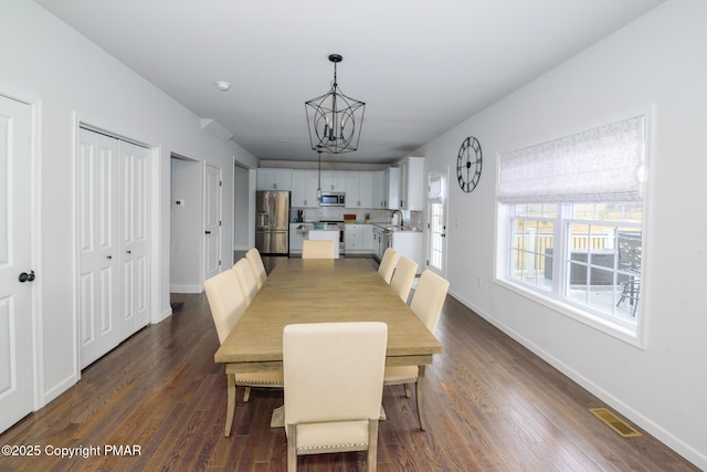 dining room featuring dark wood finished floors, a notable chandelier, visible vents, and baseboards