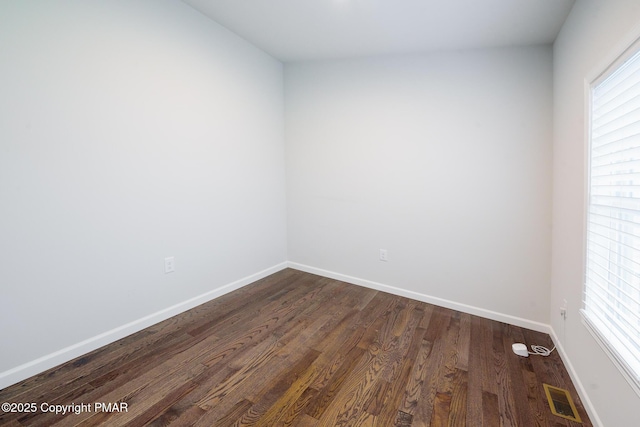 spare room with visible vents, baseboards, and dark wood-style flooring