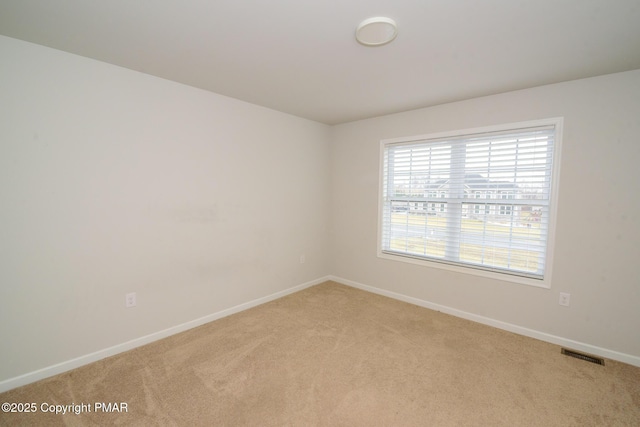 spare room featuring light carpet, visible vents, and baseboards