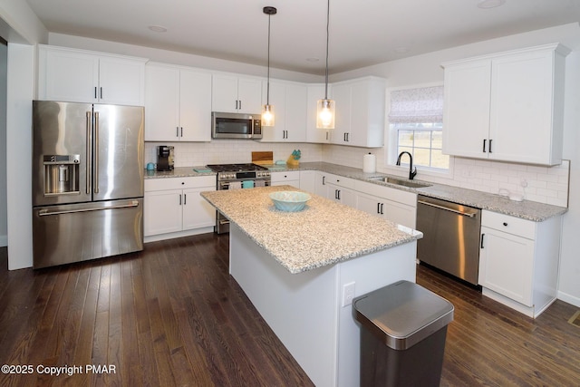 kitchen with a sink, backsplash, a kitchen island, appliances with stainless steel finishes, and dark wood-style flooring