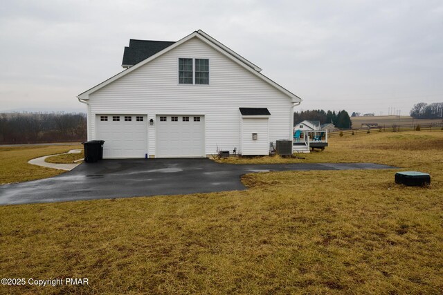 view of side of home featuring a garage, a yard, and central AC unit